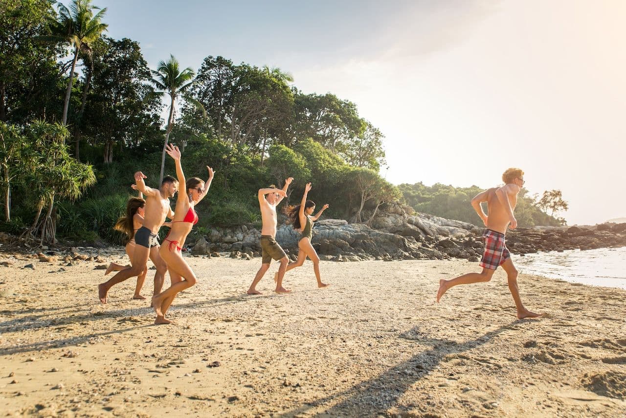 Group running down the beach into the ocean; one of the leadership retreat ideas