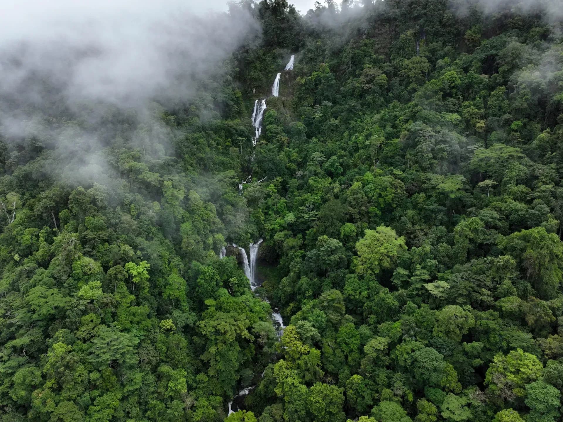 Aerial view of misty rainforest and cascading waterfalls near Vajra Jahra Retreat Center, showcasing the untouched natural beauty surrounding this Costa Rica retreat center.