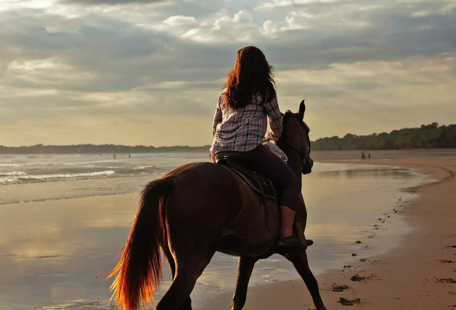 Woman horseback riding along the shoreline at sunset near Vajra Jahra Retreat Center, a serene costa rica retreat center offering beach excursions.