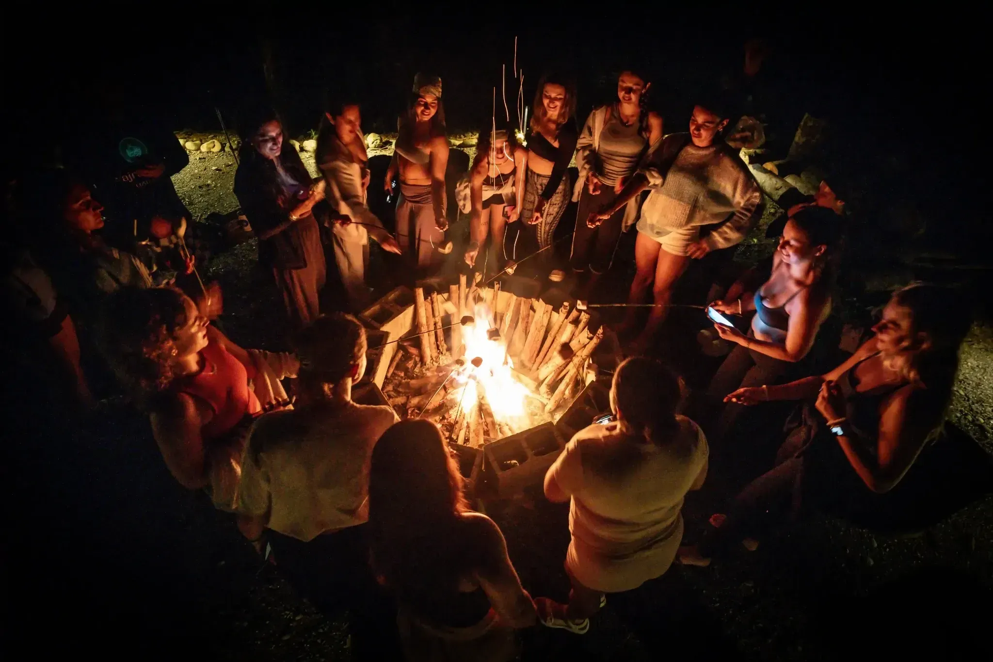 Group gathered around a glowing bonfire at Vajra Jahra Retreat Center, sharing connection and community at a Costa Rica retreat center.