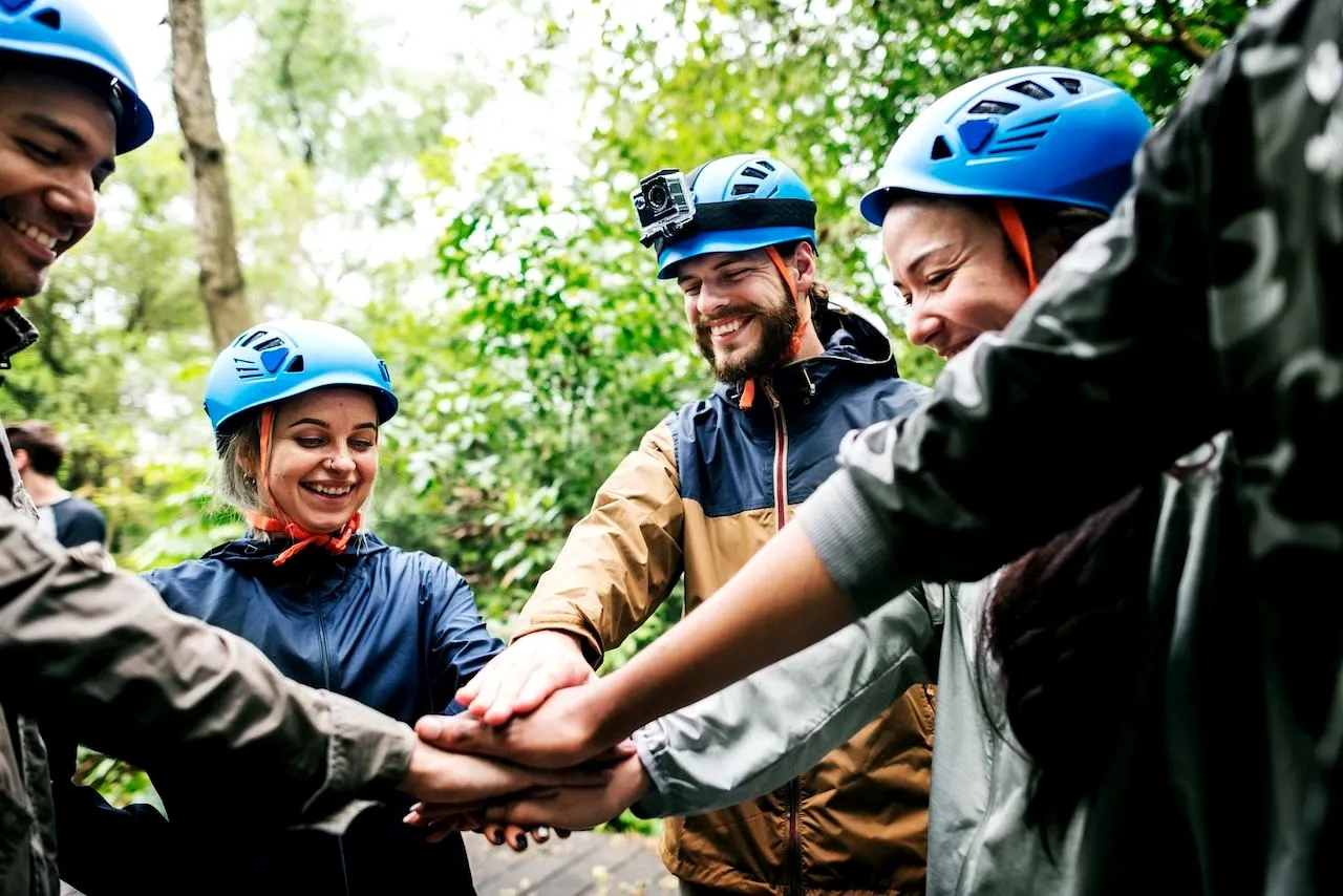 hikers in a corporate retreat with a hand on top of the other at the center of the circle