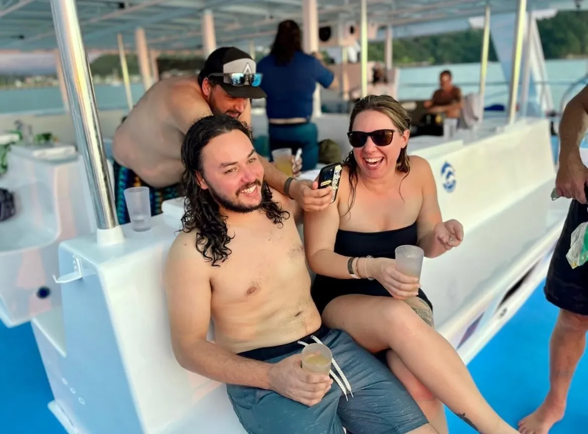 Two guests laughing on a boat during a catamaran snorkeling tour excursion.