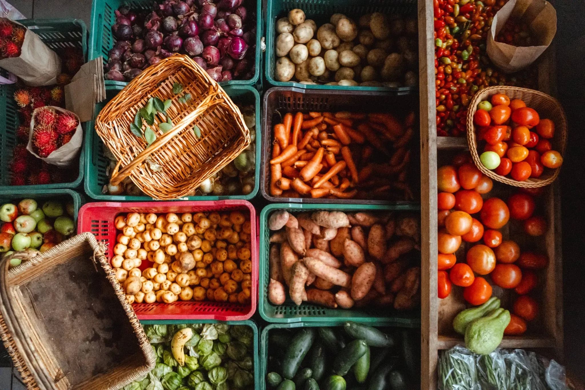 Assorted fresh vegetables and fruits arranged in baskets and crates