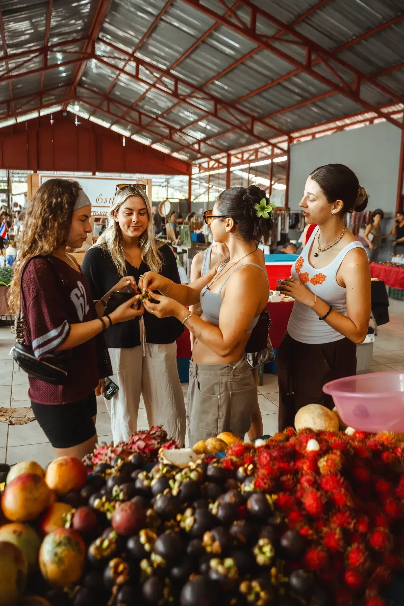 Guests exploring a local farmers market and sampling tropical fruits during San Jose Costa Rica Excursions near Vajra Jahra Retreat Center.